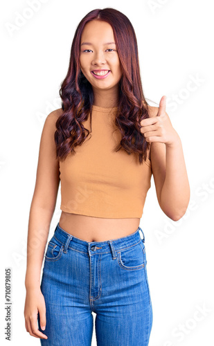 Young beautiful chinese girl wearing casual clothes smiling happy and positive  thumb up doing excellent and approval sign