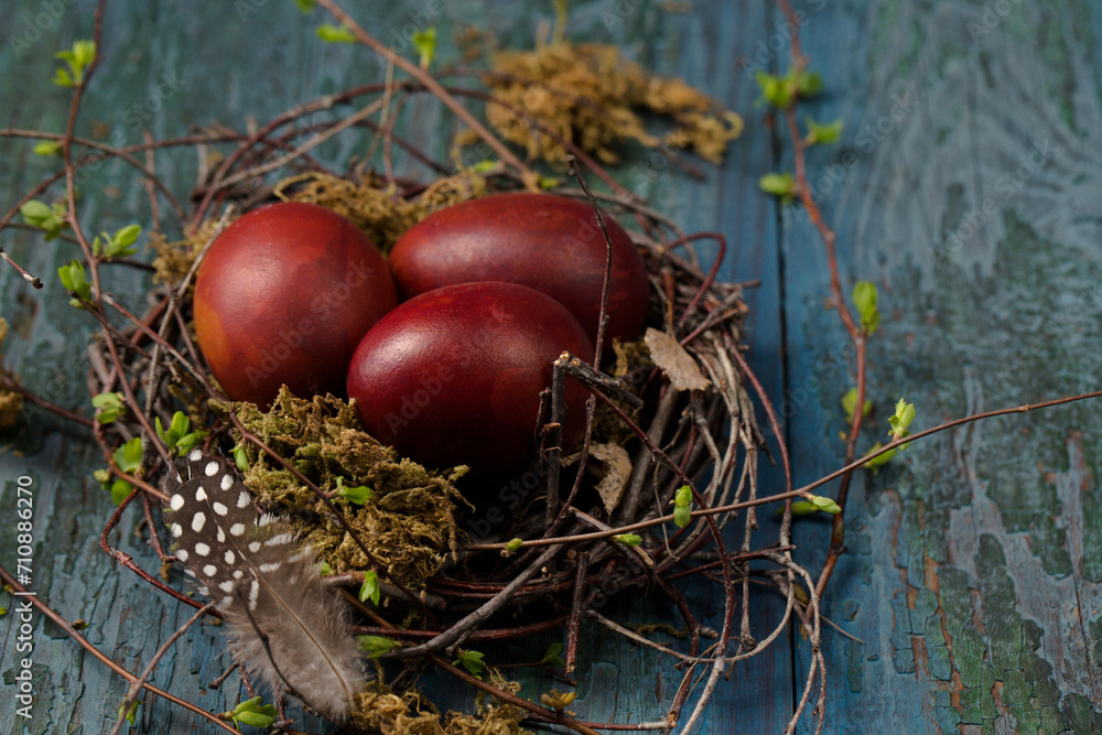 Easter eggs in a small nest made of branches and moss on a wooden background Easter eggs in a small nest made of branches and moss on a wooden background