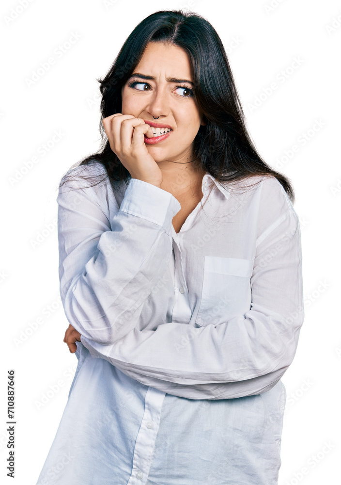 Beautiful hispanic woman wearing casual white shirt looking stressed and nervous with hands on mouth biting nails. anxiety problem. Beautiful hispanic woman wearing casual white shirt looking stressed and nervous with hands on mouth biting nails. anxiety problem.