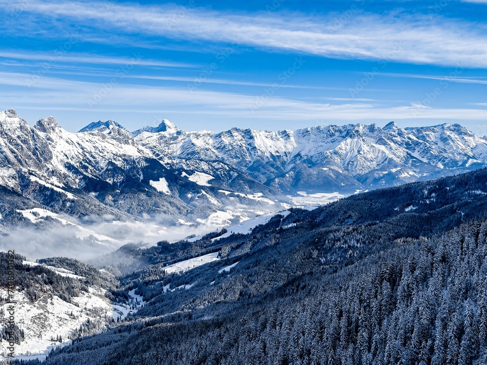 Picturesque winter scene of the Leogang Mountains covered in snow against a cloudy blue sky Austria