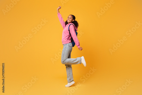 black student girl posing with blue backpack over yellow background