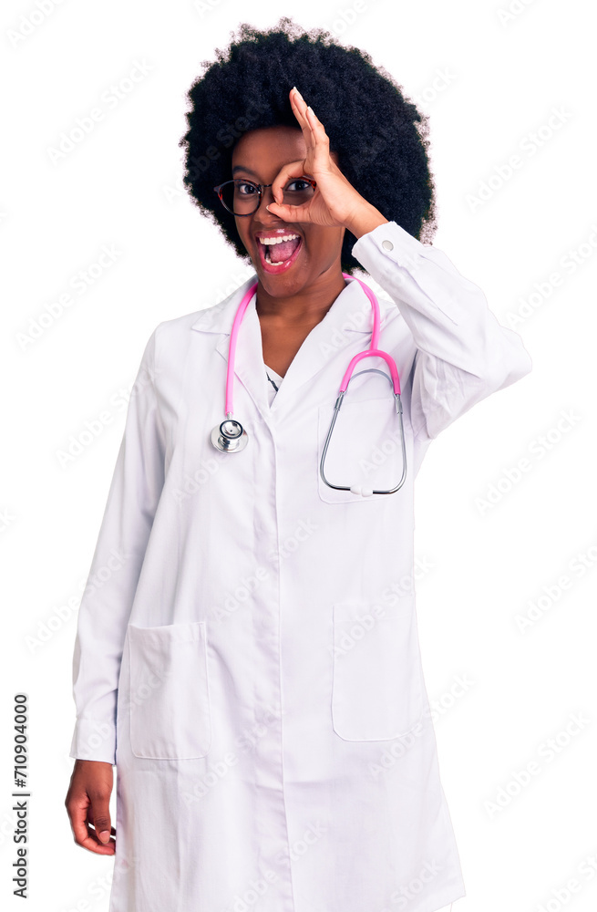 Young african american woman wearing doctor coat and stethoscope doing ok gesture with hand smiling, eye looking through fingers with happy face.