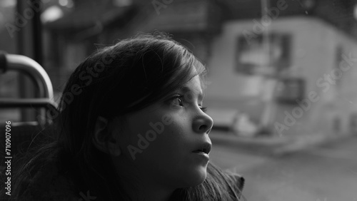 Passenger child travels by bus looking at scenery pass by in black and white, monochromatic clip of thoughtful small girl