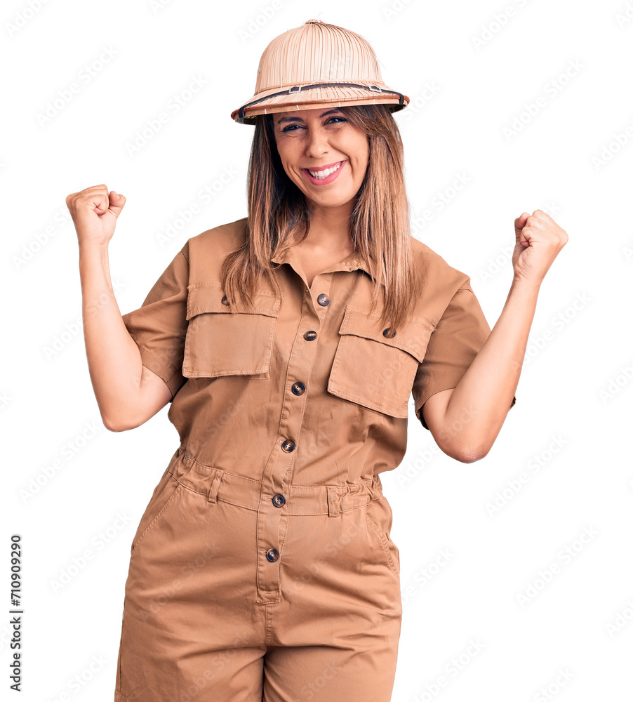 Young beautiful woman wearing explorer hat very happy and excited doing winner gesture with arms raised, smiling and screaming for success. celebration concept. Young beautiful woman wearing explorer hat very happy and excited doing winner gesture with arms raised, smiling and screaming for success. celebration concept.