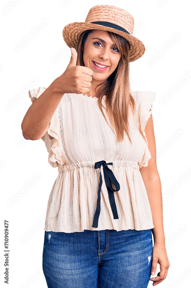 Young beautiful woman wearing summer hat and t-shirt doing happy thumbs up gesture with hand. approving expression looking at the camera showing success. Young beautiful woman wearing summer hat and t-shirt doing happy thumbs up gesture with hand. approving expression looking at the camera showing success.
