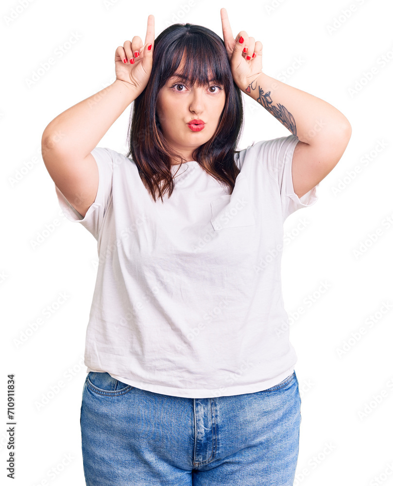 Young plus size woman wearing casual clothes doing funny gesture with finger over head as bull horns Young plus size woman wearing casual clothes doing funny gesture with finger over head as bull horns