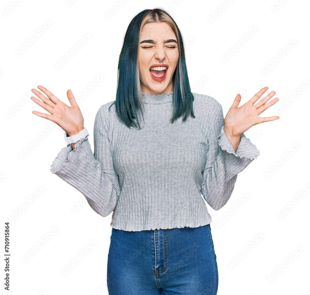 Young modern girl wearing casual sweater celebrating mad and crazy for success with arms raised and closed eyes screaming excited. winner concept Young modern girl wearing casual sweater celebrating mad and crazy for success with arms raised and closed eyes screaming excited. winner concept