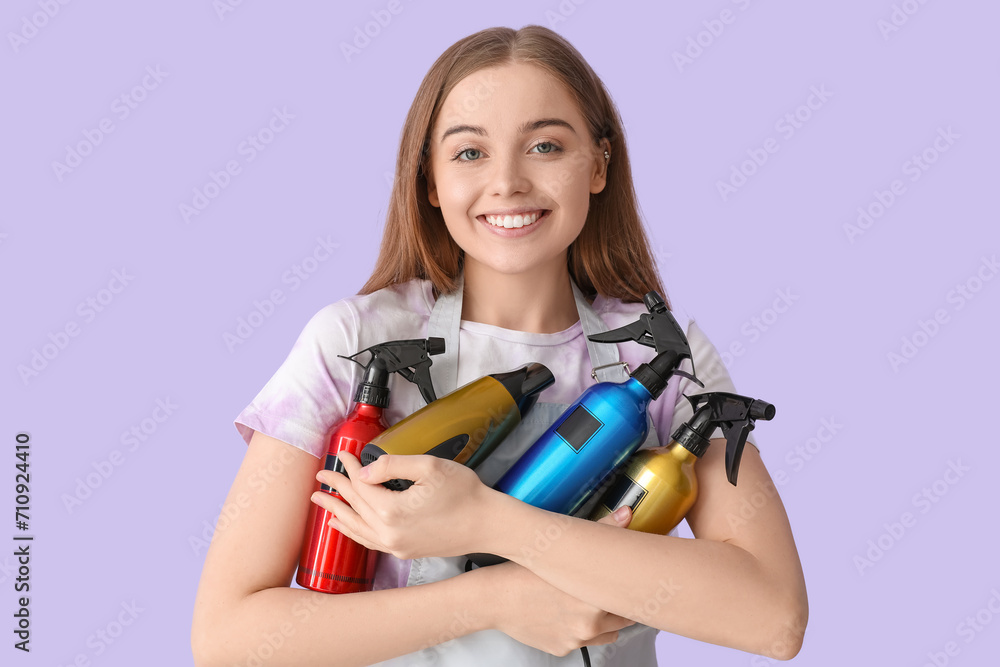 Female hairdresser with sprays and dryer on lilac background Female hairdresser with sprays and dryer on lilac background