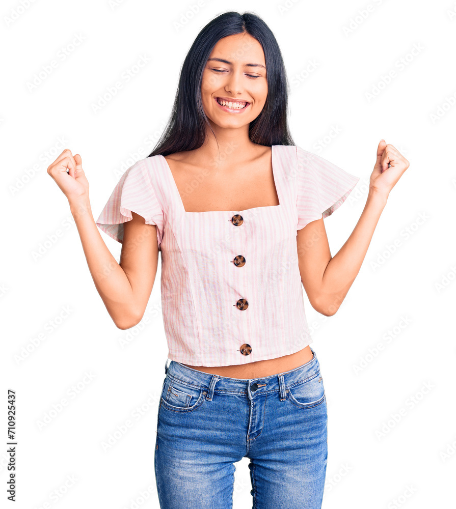 Young beautiful latin girl wearing casual clothes very happy and excited doing winner gesture with arms raised, smiling and screaming for success. celebration concept. Young beautiful latin girl wearing casual clothes very happy and excited doing winner gesture with arms raised, smiling and screaming for success. celebration concept.