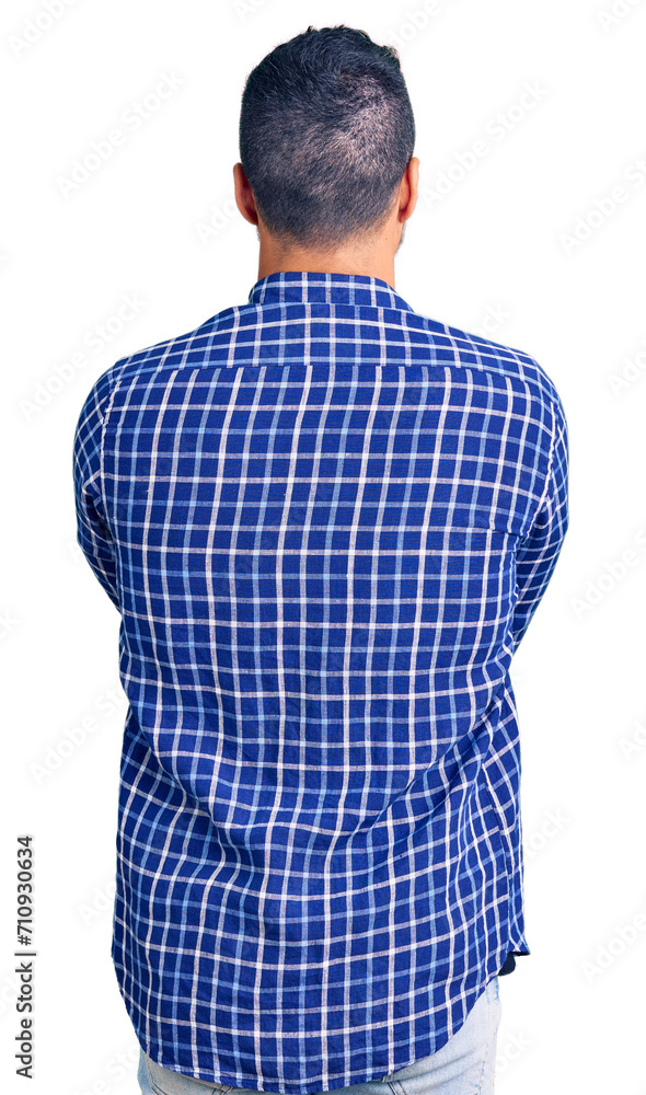 Young hispanic man wearing casual clothes standing backwards looking away with crossed arms Young hispanic man wearing casual clothes standing backwards looking away with crossed arms