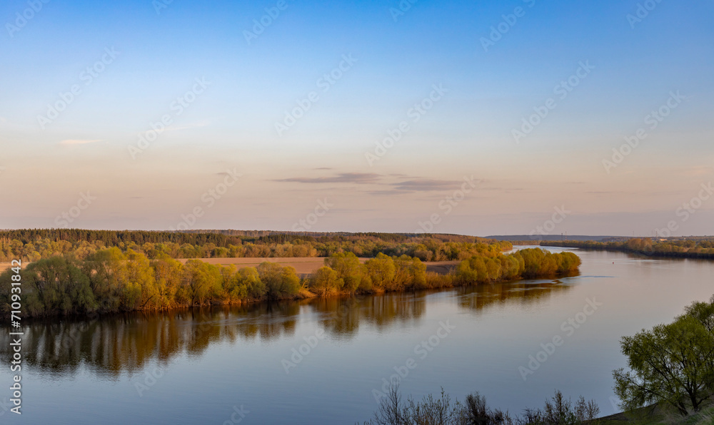 Evening landscape, early spring, a bend of a wide river, a strip of forest on the horizon