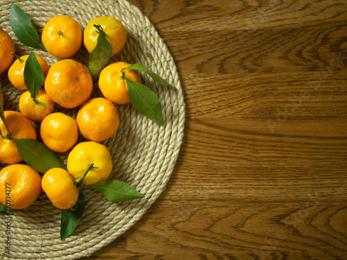 sweet and ripe tangerines with leaves on a wooden table