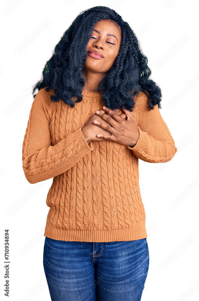 Beautiful african american woman wearing casual sweater smiling with hands on chest with closed eyes and grateful gesture on face. health concept. Beautiful african american woman wearing casual sweater smiling with hands on chest with closed eyes and grateful gesture on face. health concept.