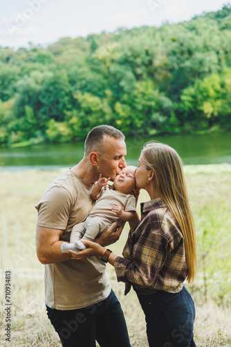 Happy young mother and father with a child on a walk in the park. The concept of a happy married couple with a child. Happy family couple with little newborn son in nature. © Дмитрий Ткачук
