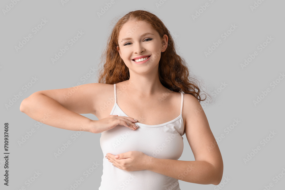 Young woman checking her breast on light background. Cancer awareness concept Young woman checking her breast on light background. Cancer awareness concept