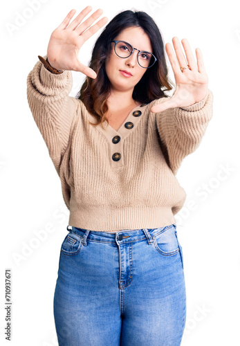 Beautiful young brunette woman wearing casual clothes and glasses doing frame using hands palms and fingers, camera perspective