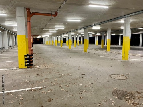 An empty parking lot at night, lit by fluorescent lights. Rows of columns with yellow paint. A solution to the city's parking problem. High quality photo