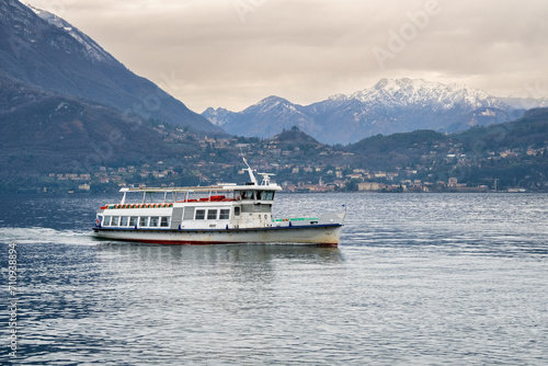 Ferry boat sails on Lake Como against the backdrop of a snow-covered mountain range