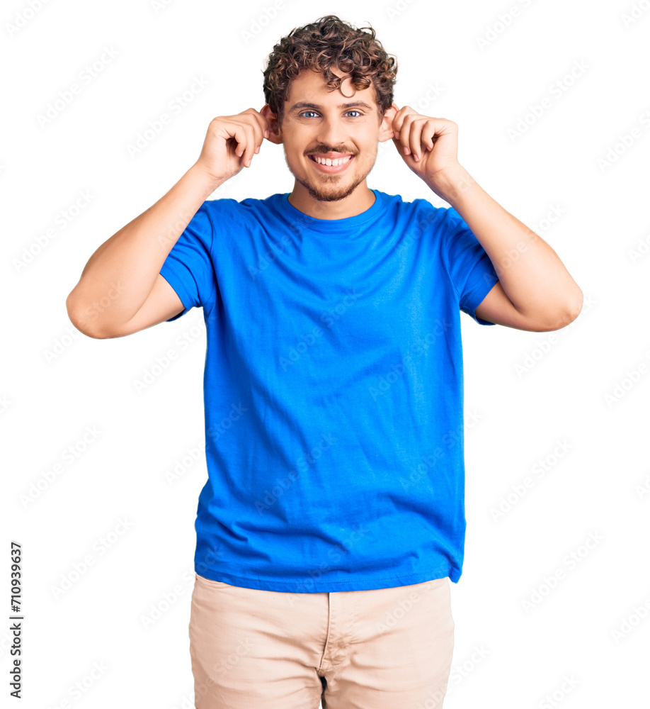 Fototapeta premium Young handsome man with curly hair wearing casual clothes smiling pulling ears with fingers, funny gesture. audition problem