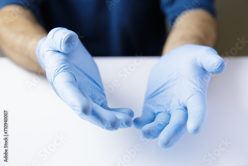 Expressive together hands of doctor or nurse wearing latex gloves on white office table. Place object.