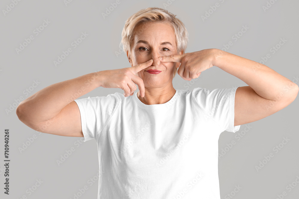Mature woman doing face building exercise on light background Mature woman doing face building exercise on light background