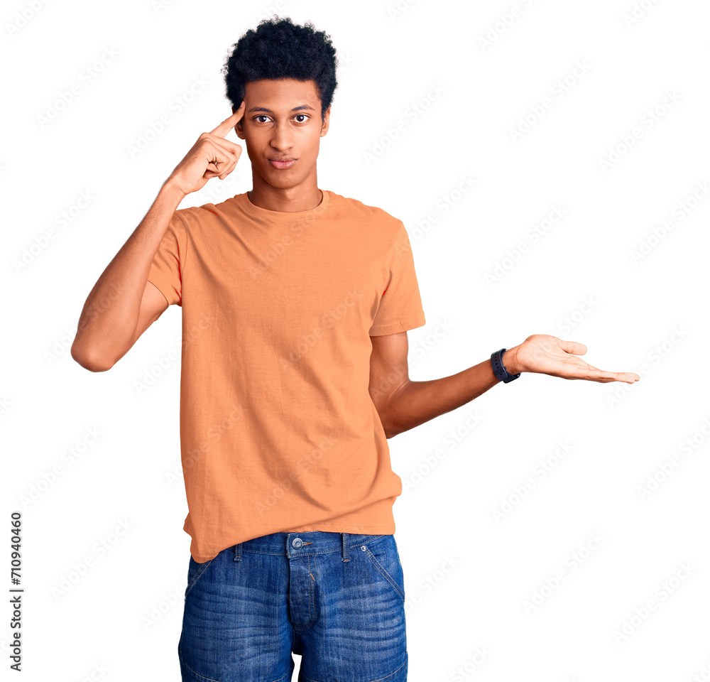 Young african american man wearing casual clothes confused and annoyed with open palm showing copy space and pointing finger to forehead. think about it.
