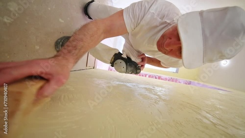 Worker in white cap is polishing yellow plaster wall. photo