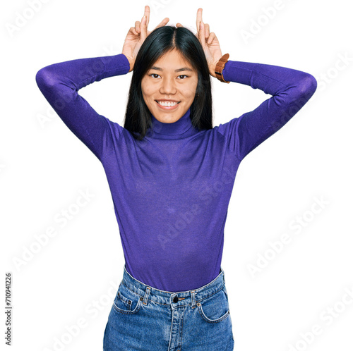 Beautiful young asian woman wearing casual clothes posing funny and crazy with fingers on head as bunny ears, smiling cheerful