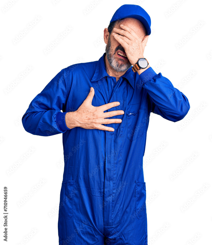 Middle age handsome man wearing mechanic uniform touching forehead for illness and fever, flu and cold, virus sick Middle age handsome man wearing mechanic uniform touching forehead for illness and fever, flu and cold, virus sick