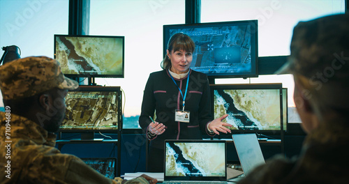 Caucasian teaching soldiers at special military lection and showing some videos on screen. Female talking to male and female mixed-races people from troops. Surveillance study concept.