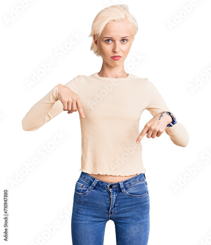 Young blonde woman wearing casual clothes pointing down looking sad and upset, indicating direction with fingers, unhappy and depressed. © Krakenimages.com