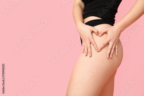 Body positive young woman in underwear making heart gesture on pink background, closeup