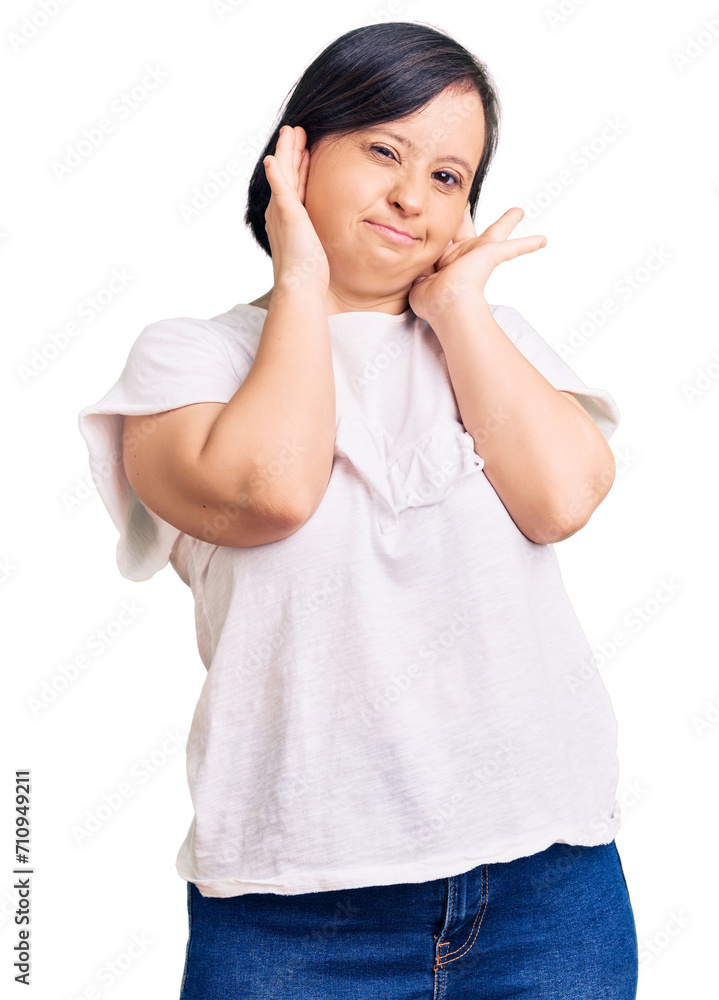 Brunette woman with down syndrome wearing casual white tshirt covering ears with fingers with annoyed expression for the noise of loud music. deaf concept. Brunette woman with down syndrome wearing casual white tshirt covering ears with fingers with annoyed expression for the noise of loud music. deaf concept.