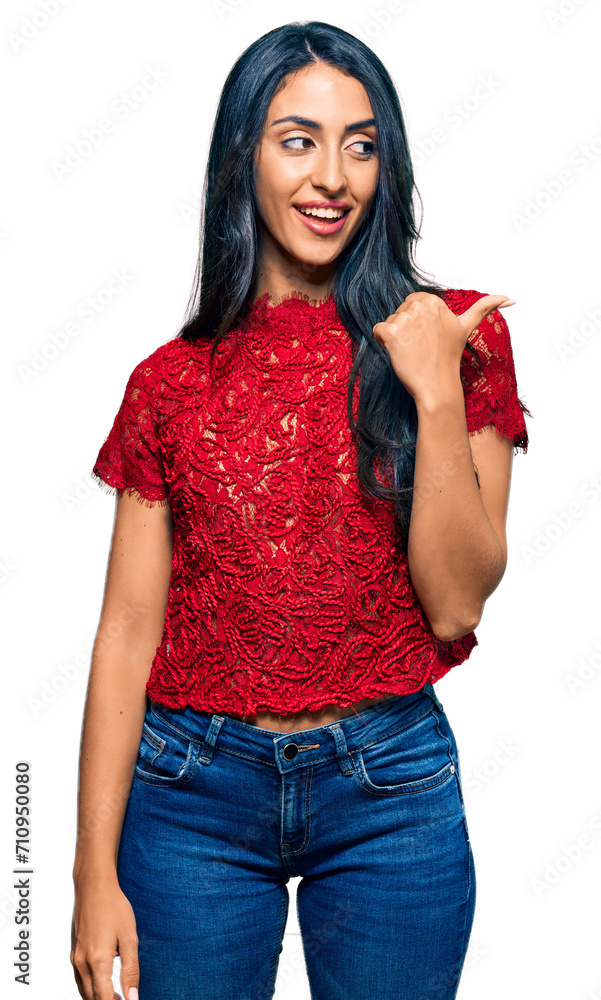 Beautiful hispanic woman wearing elegant shirt smiling with happy face looking and pointing to the side with thumb up. Beautiful hispanic woman wearing elegant shirt smiling with happy face looking and pointing to the side with thumb up.