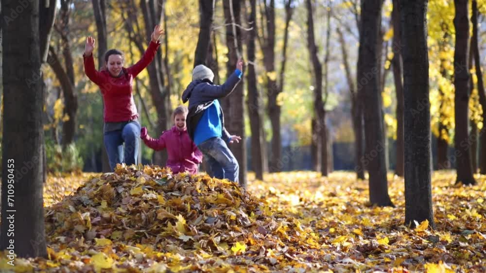 Mother and two children jump to big heap of yellow fallen leaves Mother and two children jump to big heap of yellow fallen leaves