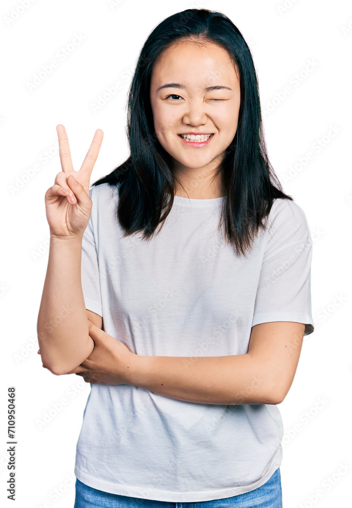 Young chinese woman wearing casual white t shirt smiling with happy face winking at the camera doing victory sign. number two. Young chinese woman wearing casual white t shirt smiling with happy face winking at the camera doing victory sign. number two.