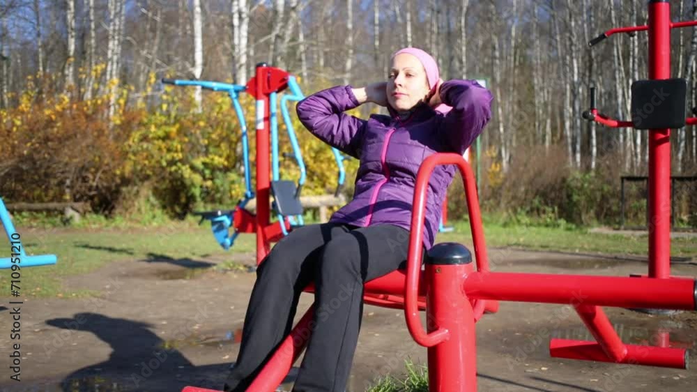Woman does exercises at simulator in park in autumn day Woman does exercises at simulator in park in autumn day