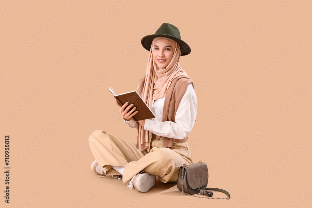 Stylish Muslim woman reading book on brown background Stylish Muslim woman reading book on brown background