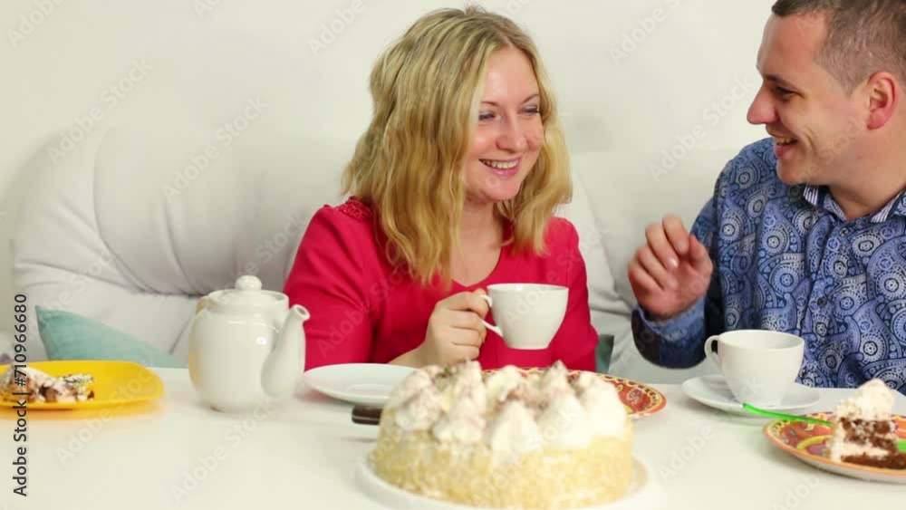 Young couple is talking and sitting on sofa at the birthday table Young couple is talking and sitting on sofa at the birthday table
