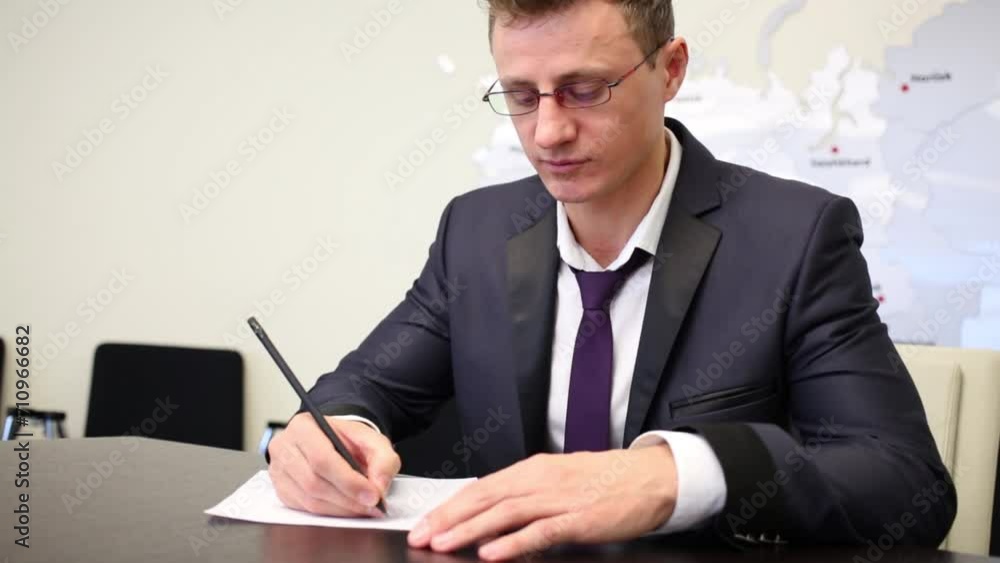businessman in suit sits at table and puts down by pencil businessman in suit sits at table and puts down by pencil