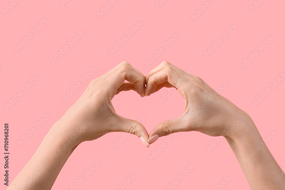 Obraz premium Female hands showing heart gesture on pink background. Valentine's Day celebration