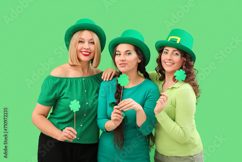 Happy women with paper clovers on green background. St. Patrick's Day