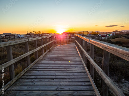 Wooden path leading to the beach at sunset by the sea