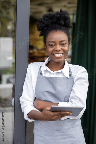 Smiling young woman standing in a cafe door and feeling positive