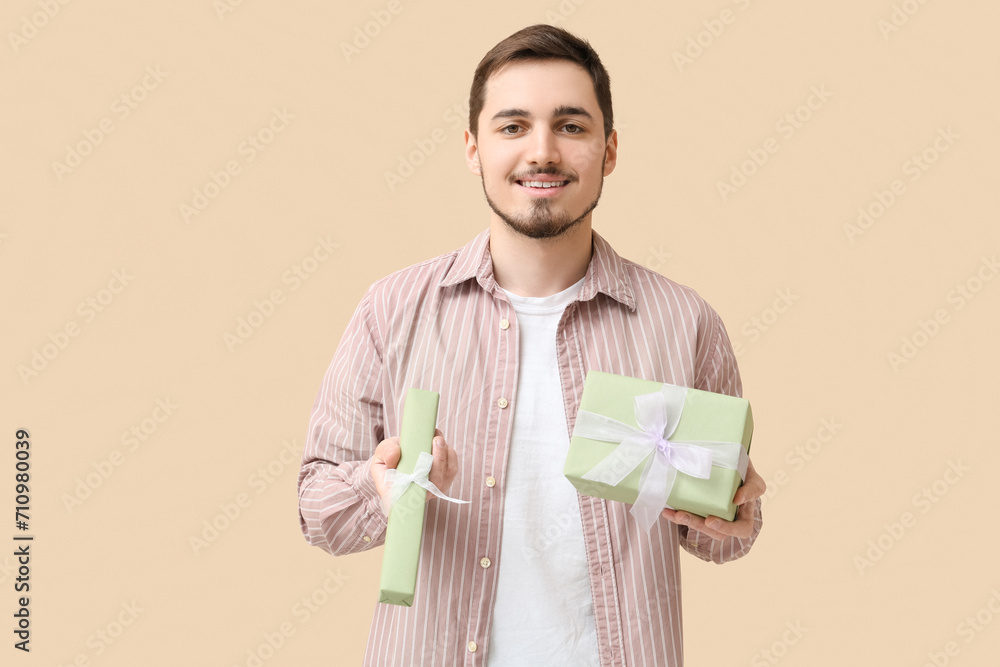 Young man with gift boxes on beige background. International Women's Day