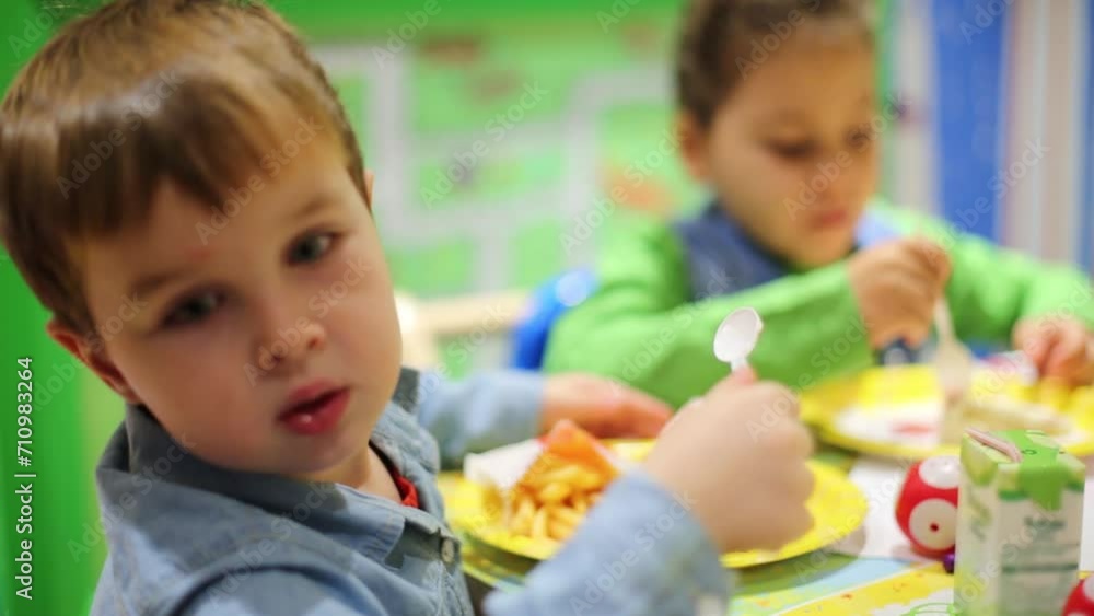Little boy and girl eat cake by spoons at birthday. Focus on boy Little boy and girl eat cake by spoons at birthday. Focus on boy