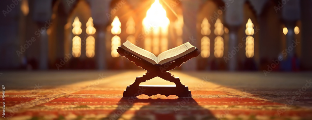 Sacred Book Opened on a Stand with Sunlight Streaming Through Windows. An open holy Quran basks in the golden sunlight, divine glow on its pages, peaceful reverence in a place of worship. Panorama.