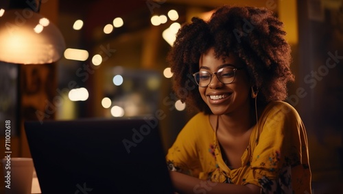 Black woman smiling while using laptop at night