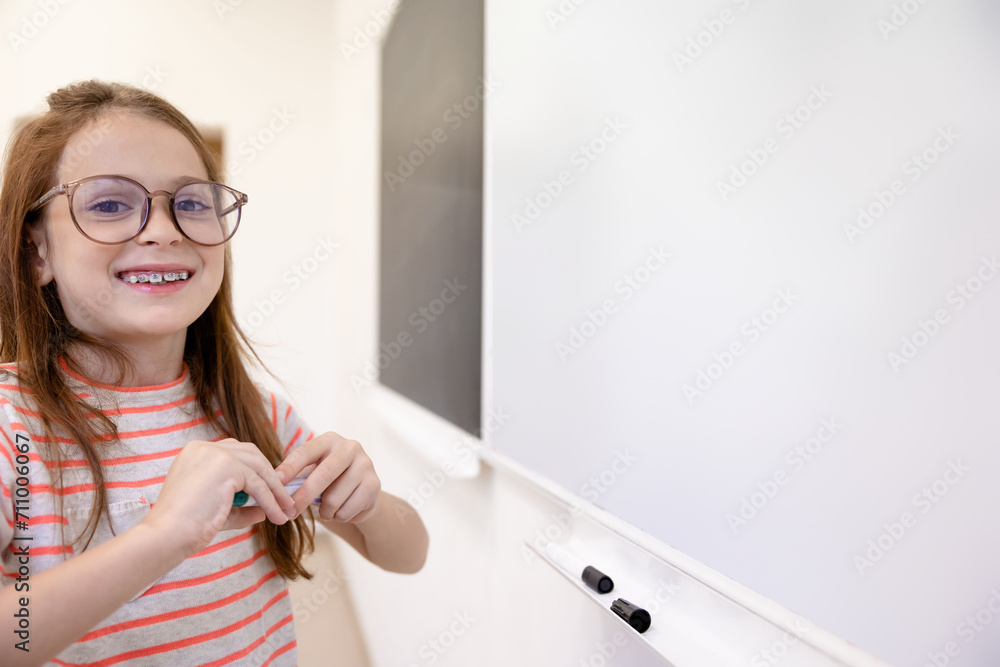 Pupil girl doing mathematics task on while board during lesson. Pupil girl doing mathematics task on while board during lesson.