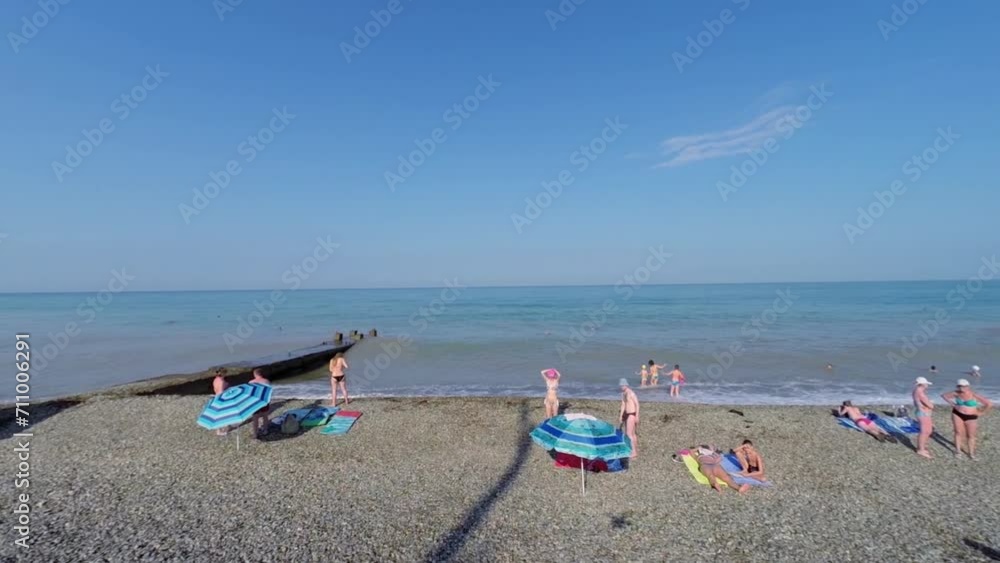 People get rest on sea beach with stone moorage at summer People get rest on sea beach with stone moorage at summer
